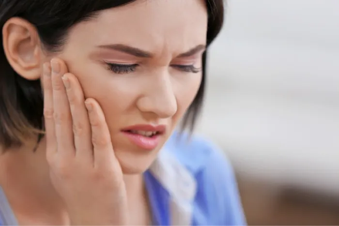 woman holding jaw due to TMJ Disorder