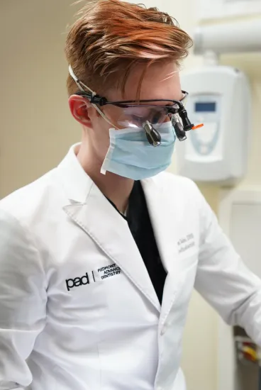 dentist wearing mask and vision aides to perform dental examination